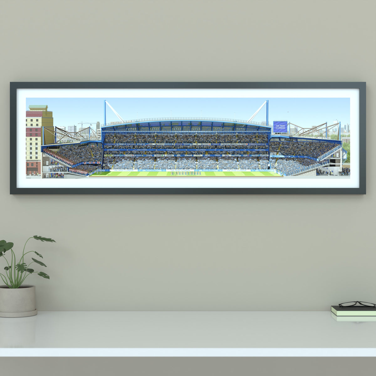 A framed panoramic print of a Chelsea FC’s Stamford Bridge stadium, displayed on a light gray wall.