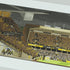 A panoramic art print of a Wolves' Molineux stadium, mounted on a light gray wall. The print features a detailed illustration of a stadium filled with yellow and black clad fans under a dark sky.